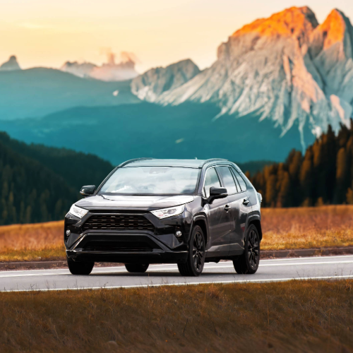 gray car on the side of the road with a view of the mountains at sunset